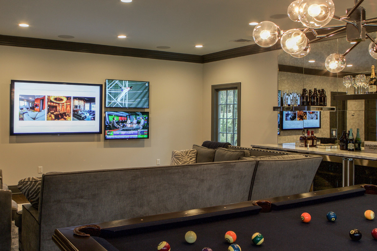 comfortable sports room in a home with tvs on the wall, recessed lighting, a billiards table and a small bar.